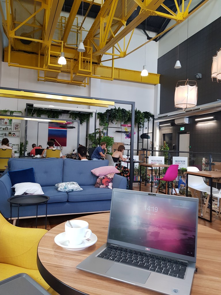 A vibrant coworking space with laptops and couches, essential for productivity in what is a digital nomad routine.
