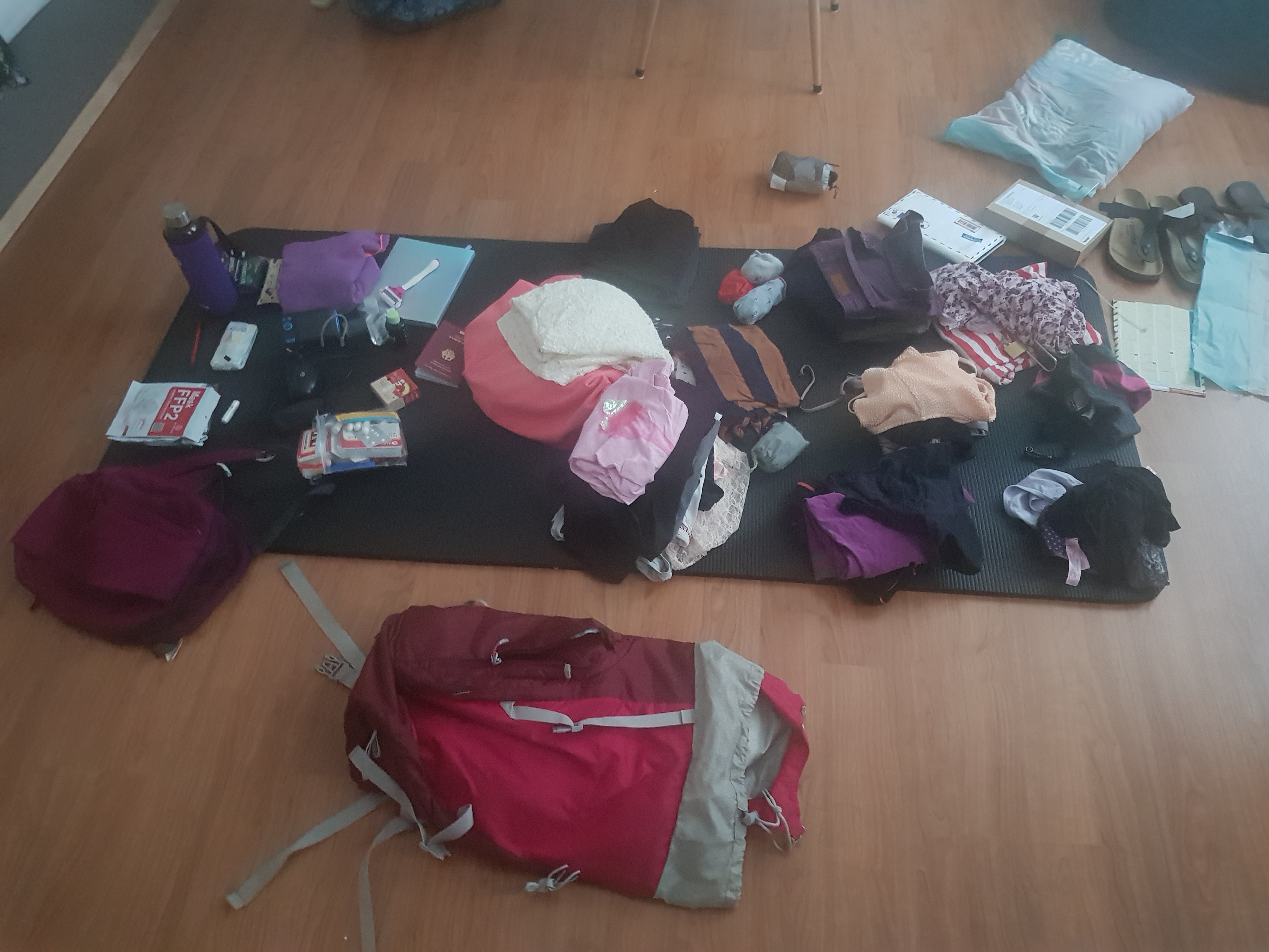 Travel gear and clothes laid out on the floor, preparing for a trip.