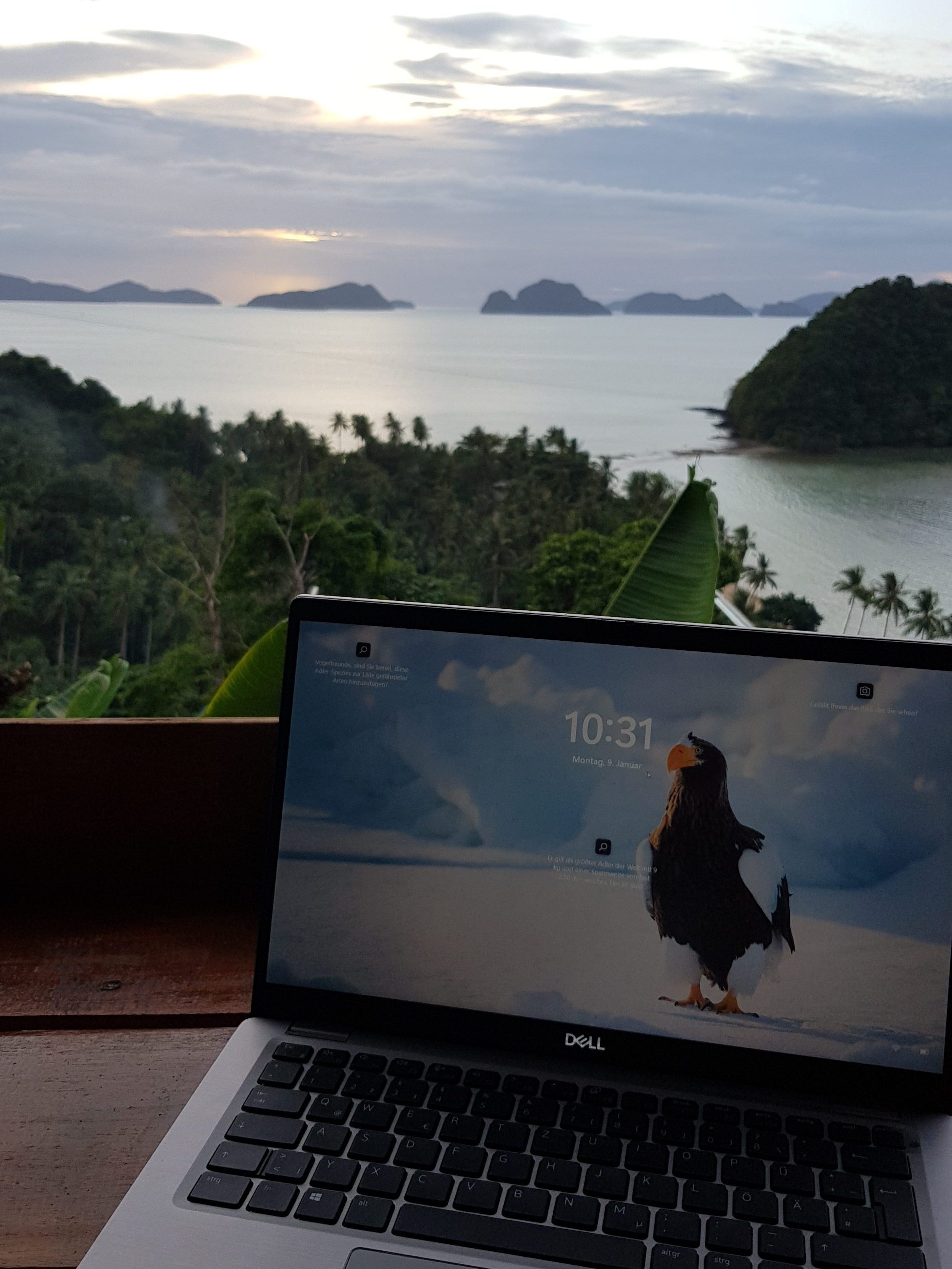 Remote work setup with a laptop overlooking a tropical landscape and ocean view in El Nido, Philippines