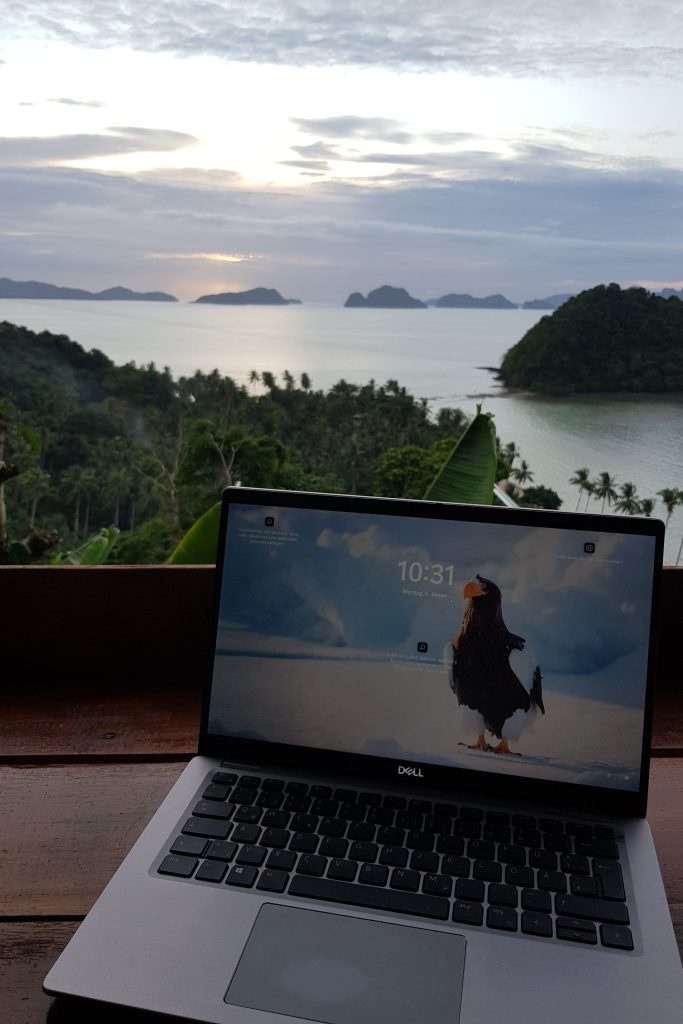 A laptop on a desk with a tropical island view in the Philippines, illustrating "how to become a digital nomad" lifestyle.