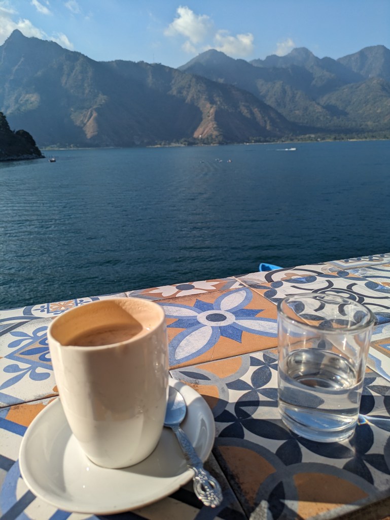 Cup of coffee overlooking Lake Atitlan with mountain views, a serene morning for digital nomads in Guatemala.
