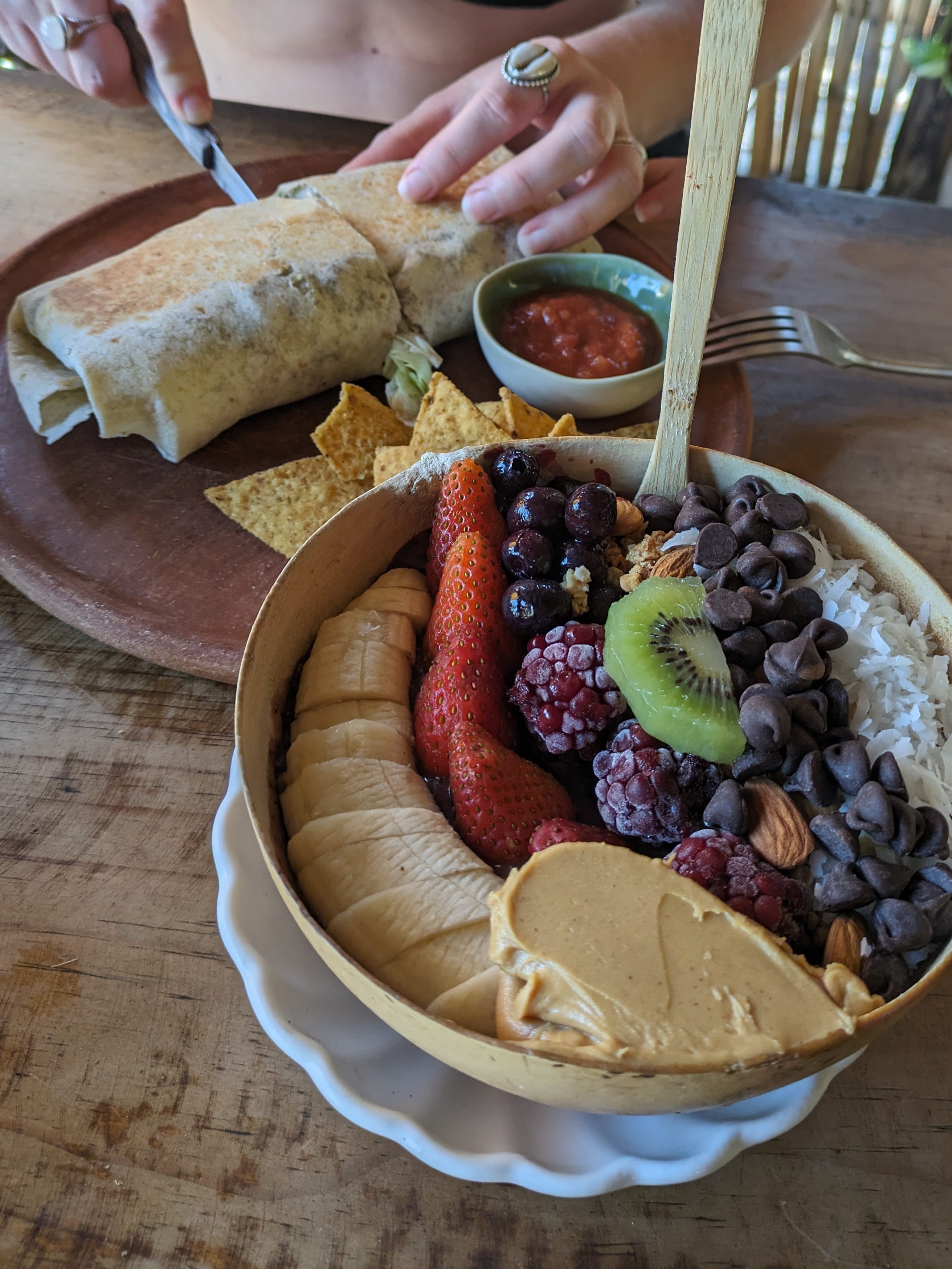 Healthy breakfast bowl with fresh fruit, granola, and peanut butter, alongside a burrito, enjoyed by digital nomads in Guatemala.