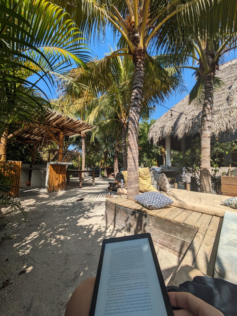 Reading a book in a cozy hammock under palm trees, a peaceful work spot for digital nomads in Guatemala.
