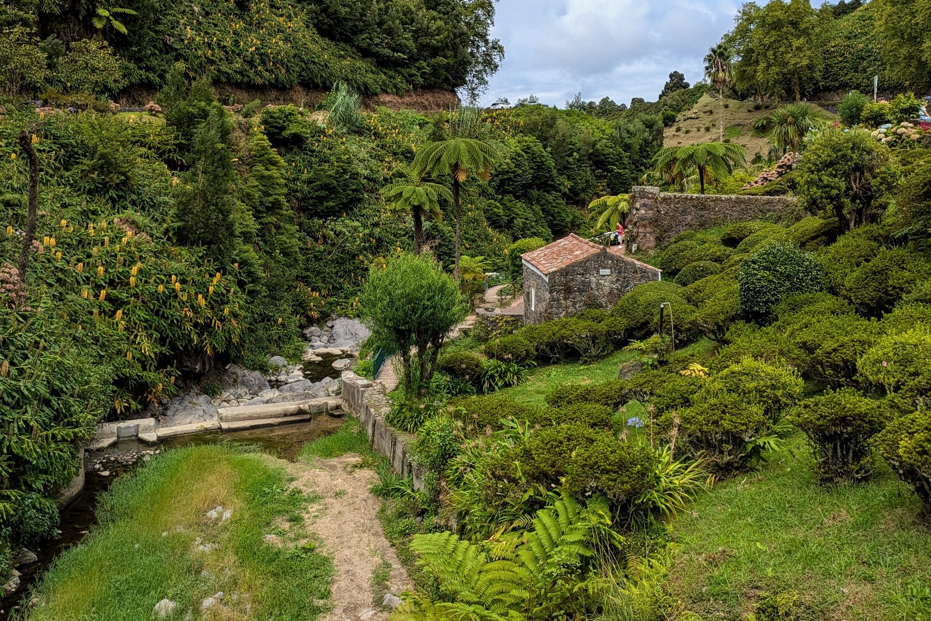 Lush green garden with stone paths and a small house, a serene retreat for digital nomads in the Azores.