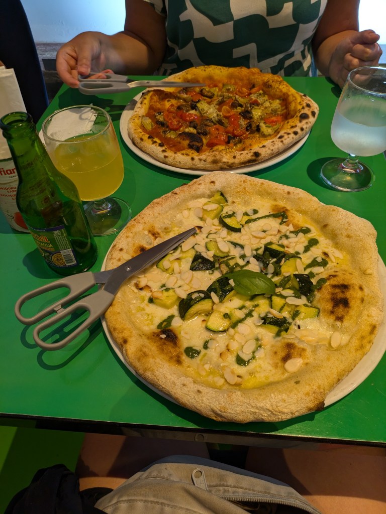 A table with fresh pizzas and drinks, highlighting simple pleasures in "what is a digital nomad" lifestyle while traveling.
