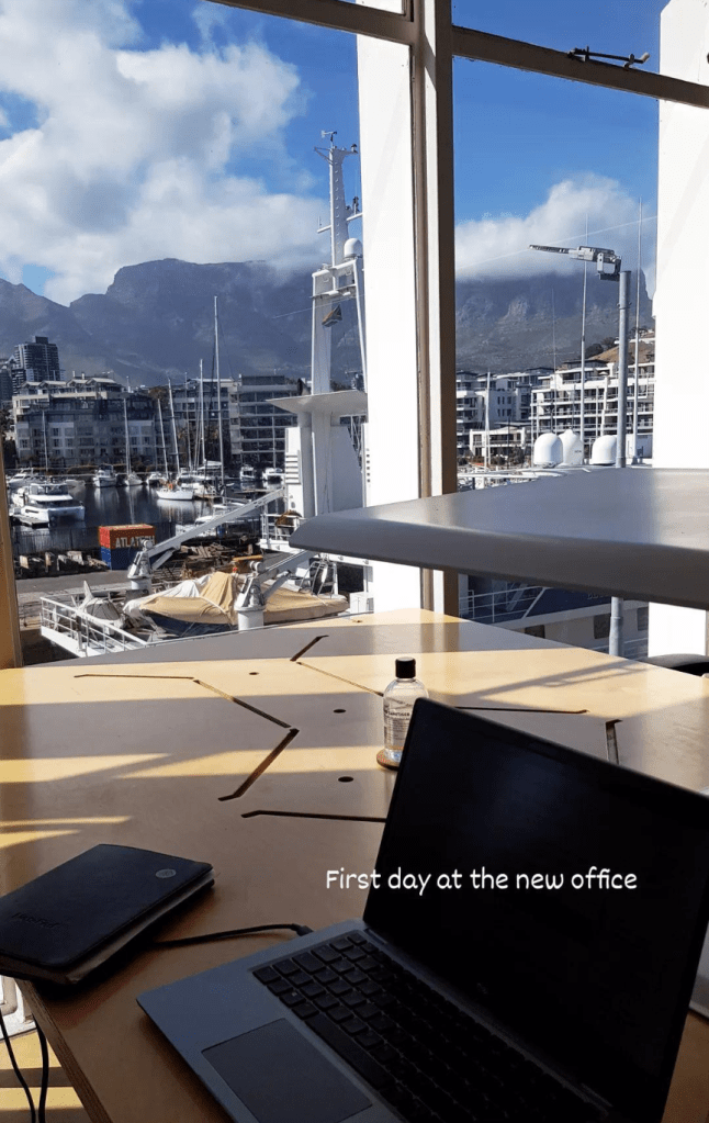 Laptop setup with a view of Cape Town’s harbor and Table Mountain in South Africa, carribean island with palm trees and small houses, without backpacking problems.