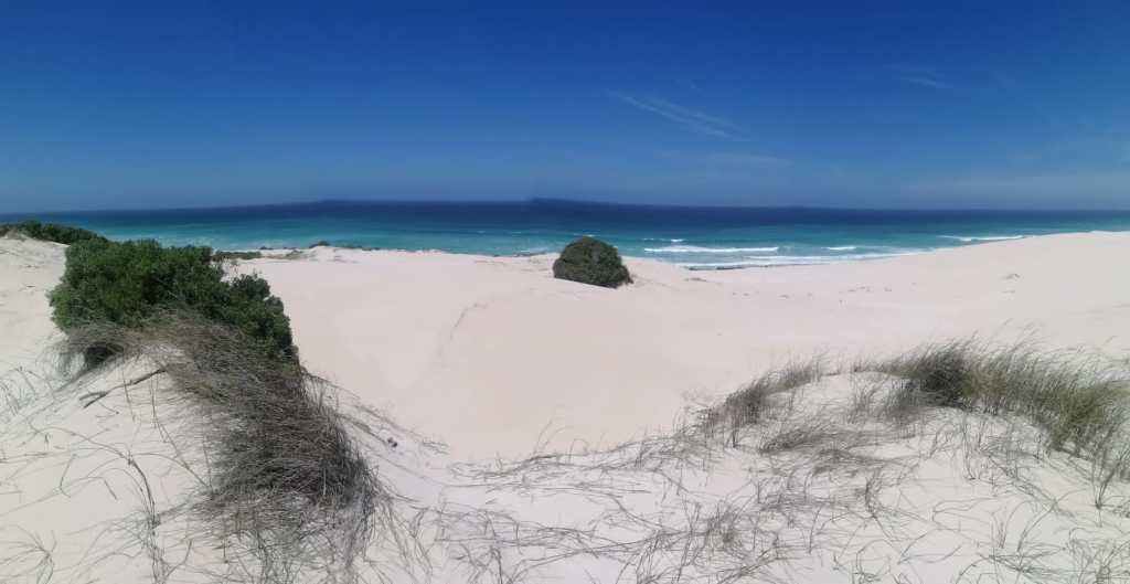 White sandy beach with clear blue skies, a serene spot for digital nomads Cape Town.