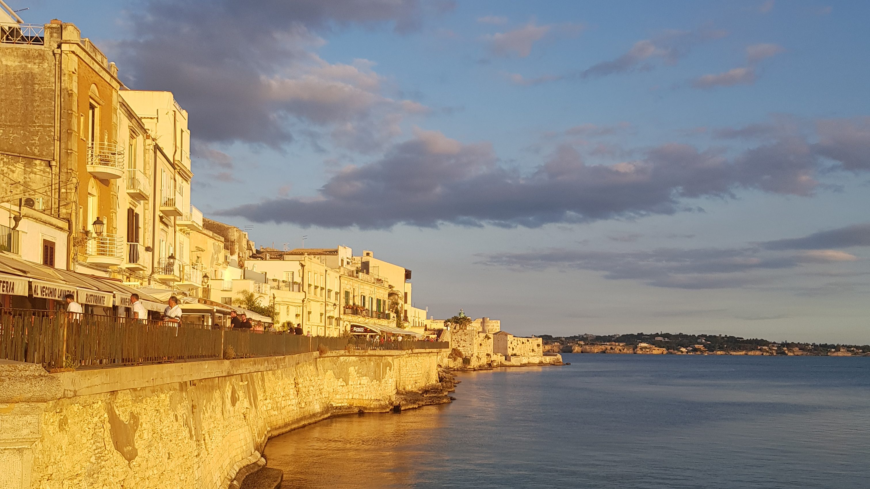 A sunset view of coastal buildings in Sicily, capturing the charm of "how to become a digital nomad" while exploring historic destinations