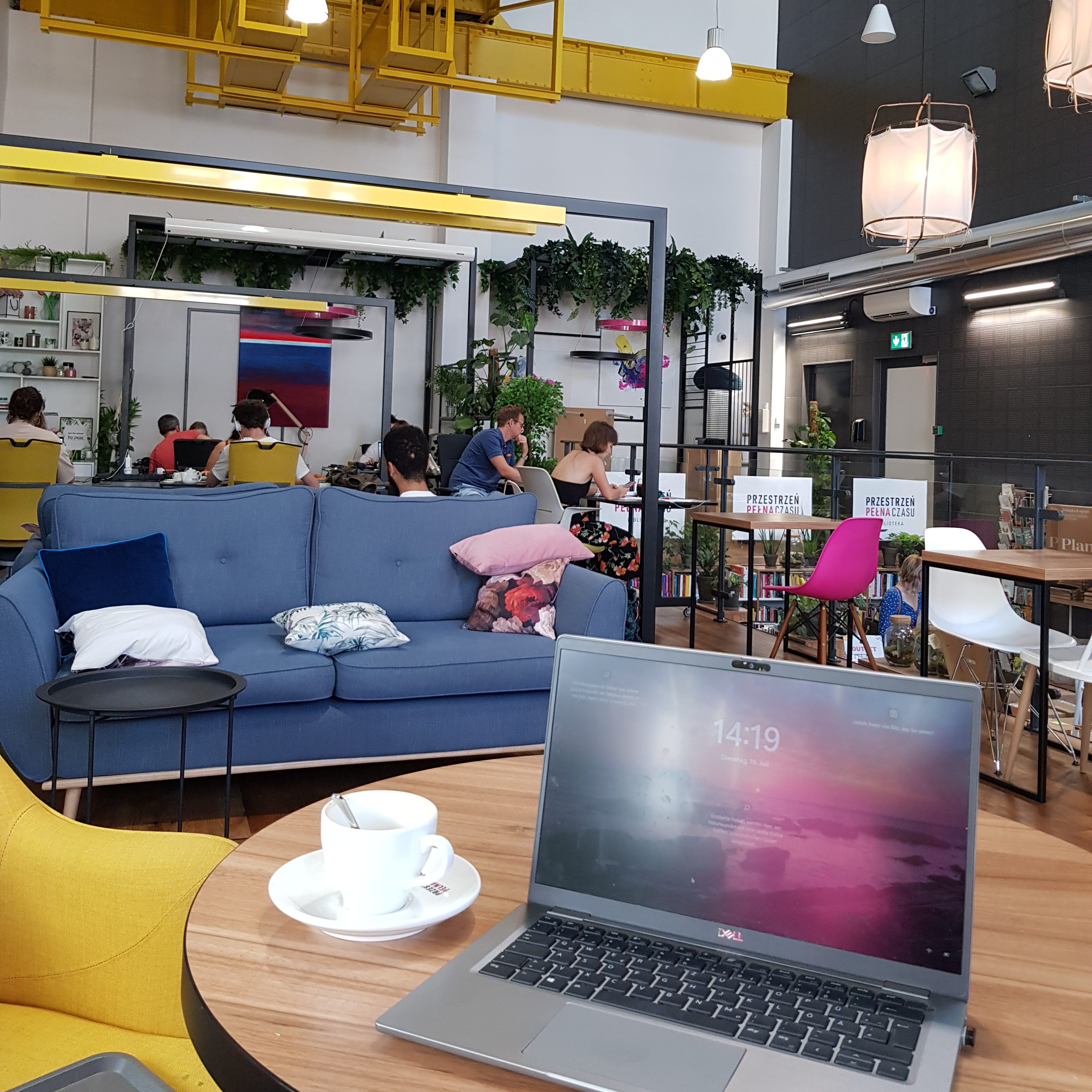 A laptop and coffee in a cozy coworking space in Krakow, showcasing "how to become a digital nomad" while working remotely.