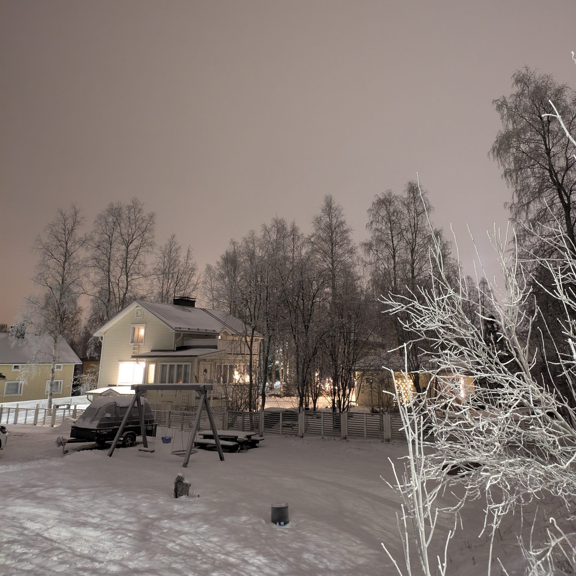 A serene snowy village scene under a night sky in Rovaniemi, Lapland, Finland.