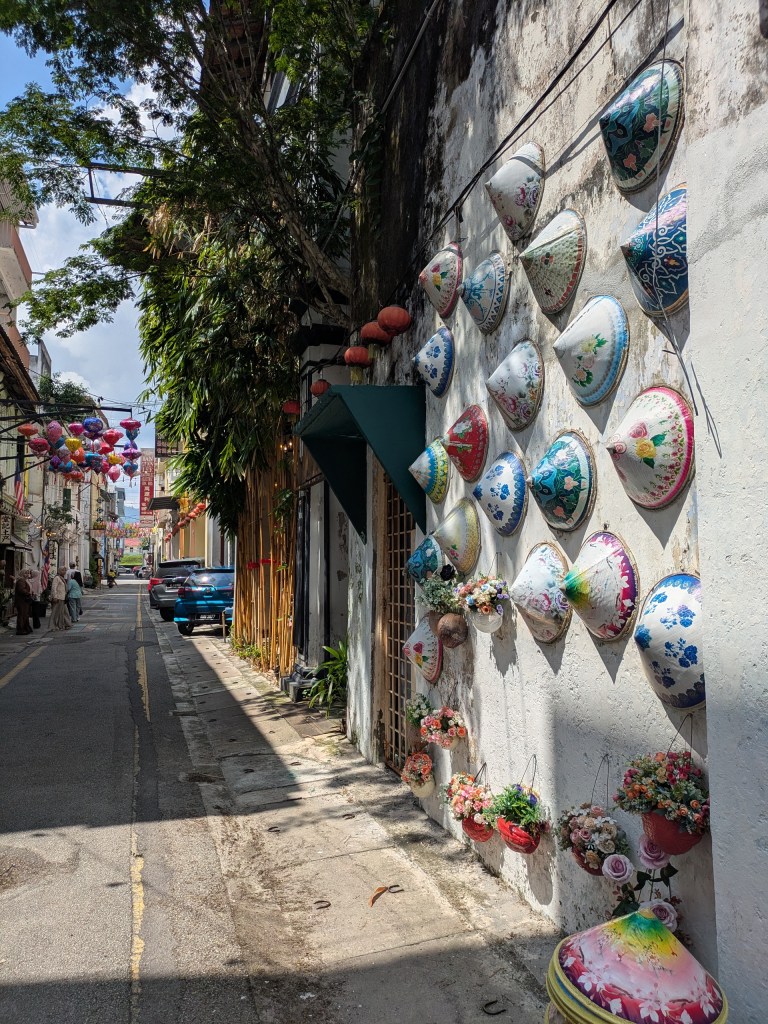 Colorful wall art featuring traditional hats in Ipoh's Old Town, a vibrant area for digital nomads in Malaysia