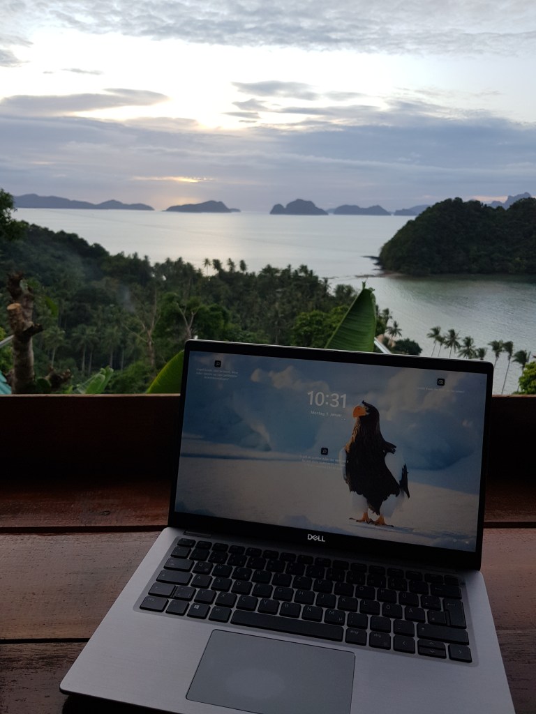 Laptop on a table overlooking a tropical beach at sunset in, without backpacking problems.