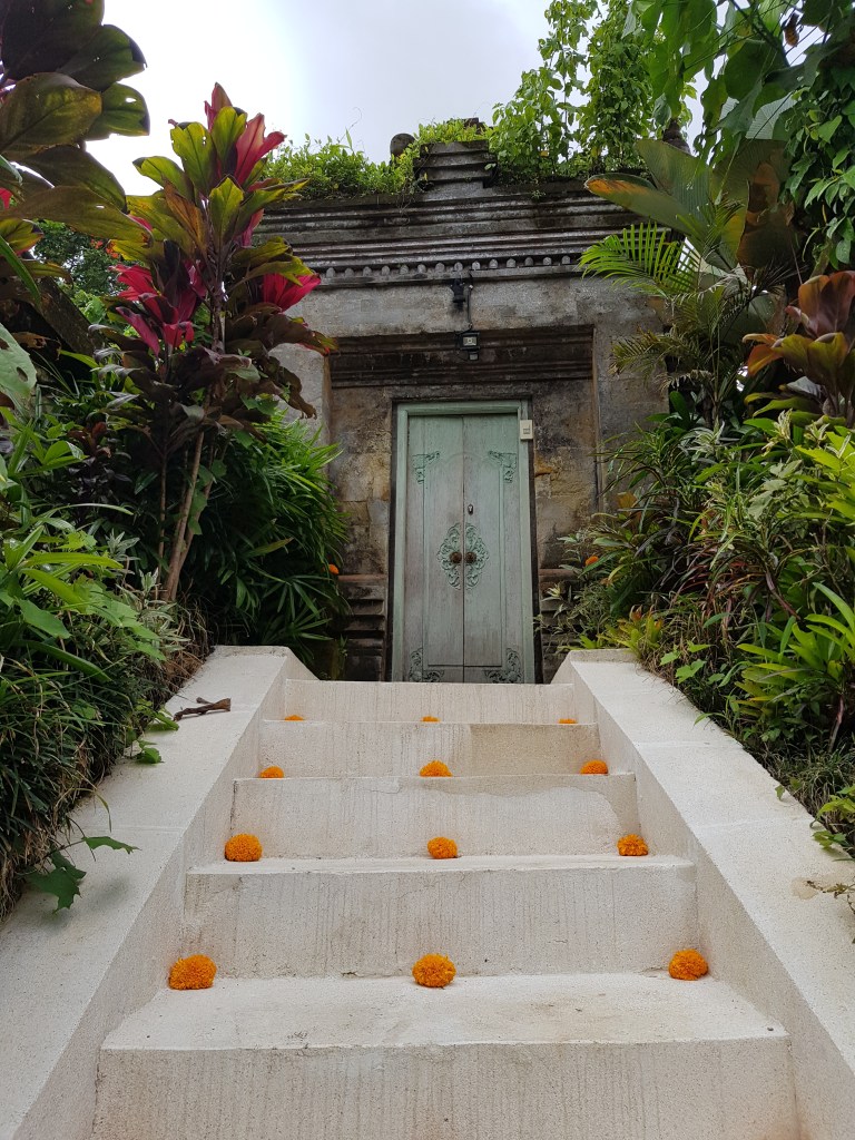 Traditionelles Balinesisches Tor mit Treppe und Blumen – Kultur erleben beim Backpacking in Bali, Ubud.