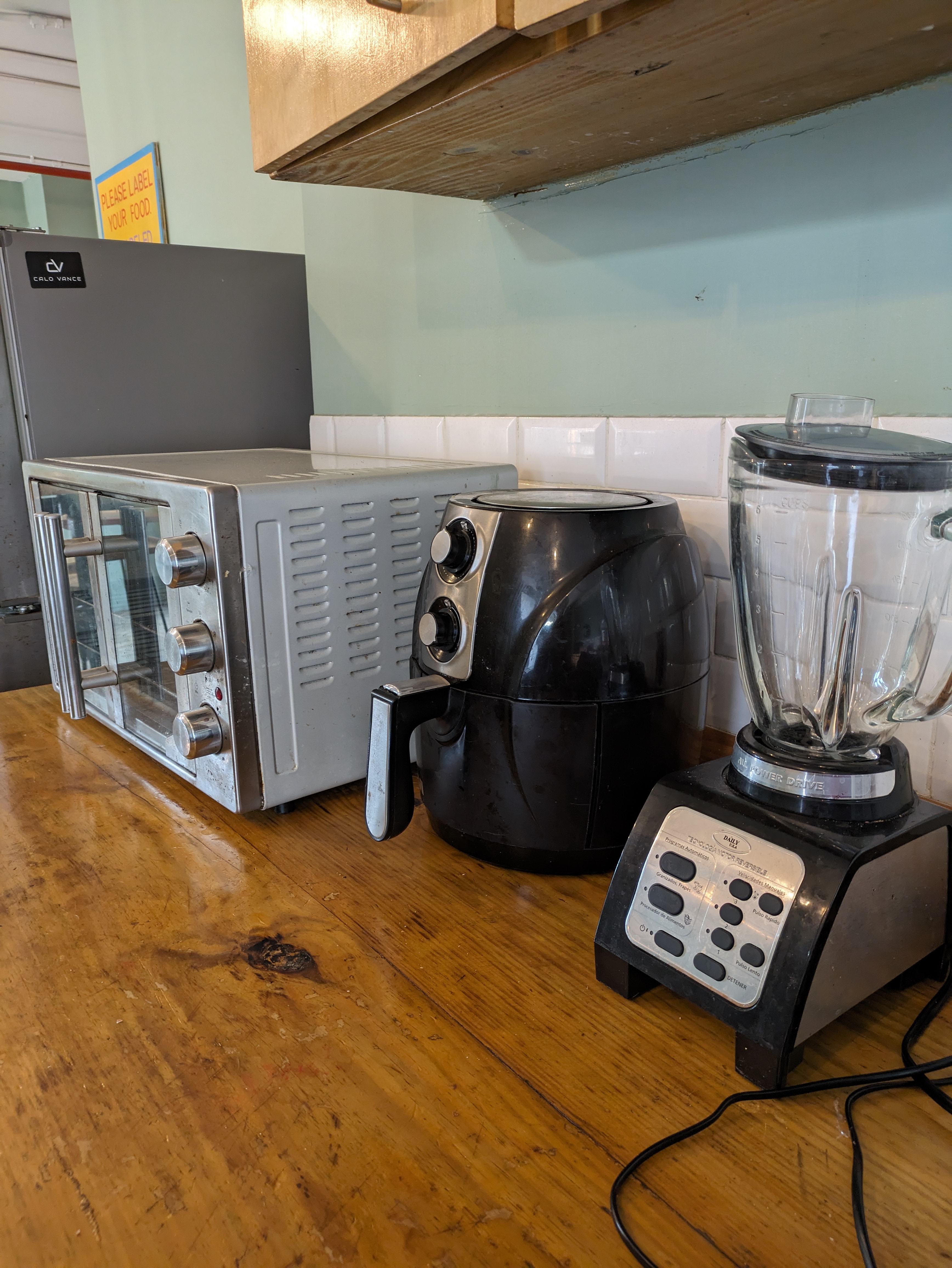 A countertop with a microwave, an air fryer, and a USB-powered travel blender in a shared kitchen.